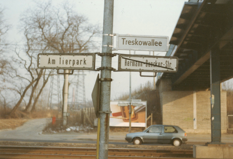Straßenschilder in Berlin an Laternenmast. Oberhalb das neue Straßenschild, unterhalb das alte Schild mit überklebter Bezeichnung